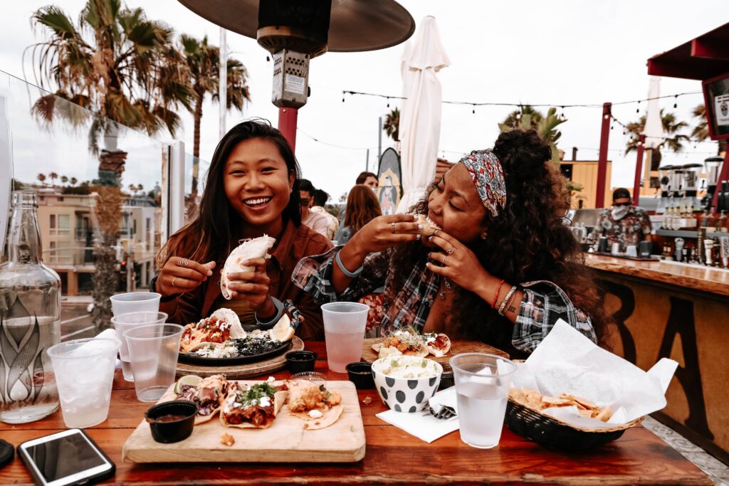 Two happy girls eating at a restaurant around the murray house san diego